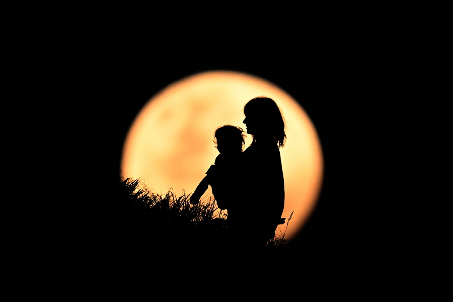 Μία μητέρα αγκαλιά με το παιδί της βλέπει την πανσέληνο να ξεπροβάλλει, σε πάρκο της Αυστραλίας