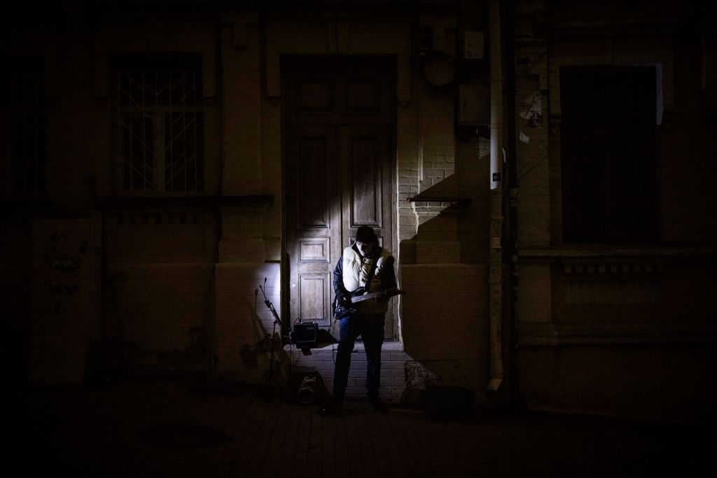 Μουσικός παίζει κιθάρα σε έναν σκοτεινό, άδειο δρόμο του Κιέβου