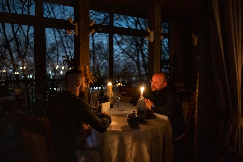 Υπό το φως των κεριών, δύο άνδρες δειπνούν σε εστιατόριο της ουκρανικής πρωτεύουσας