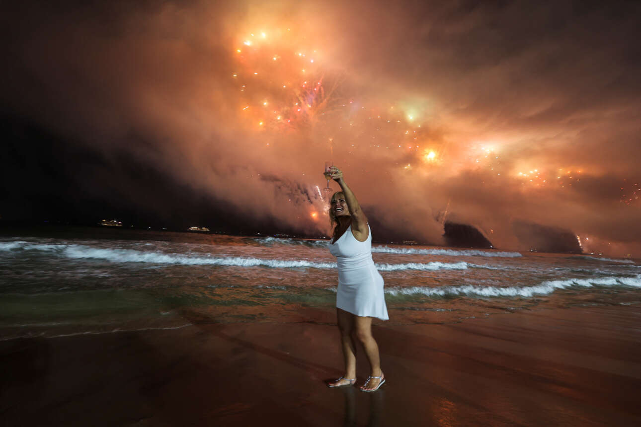 Ρίο ντε Τζανέιρο, Βραζιλία. Μια πρόποση στην παραλία, ενώ ο ουρανός έχει πάρει φωτιά από τα πυροτεχνήματα