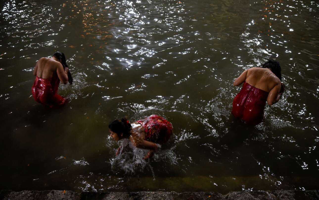 «Ιερό» μπάνιο σε ποτάμι του Κατμαντού, στο πλαίσιο ινδουιστικού φεστιβάλ – πρωταγωνίστριες σε αυτό το νεπαλέζικο έθιμο είναι οι γυναίκες, απαραιτήτως ντυμένες με κόκκινα φουστάνια, οι οποίες τηρούν και ειδική νηστεία τρώγοντας μη καρυκευμένα φαγητά