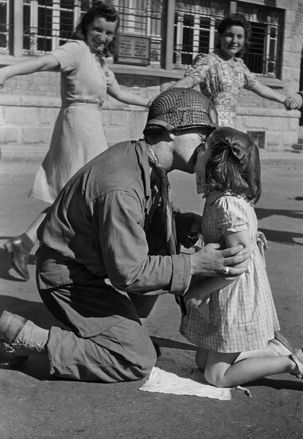 Το «Φιλί της Απελευθέρωσης»: ο λοχίας Τζιν Κοστάντζο γονατίζει για να φιλήσει ένα κοριτσάκι, μέσα στους αυθόρμητους πανηγυρισμούς που λαμβάνουν χώρα στην κεντρική πλατεία της γαλλικής πόλης Σεν Μπριάκ, τον Αύγουστο του 1944