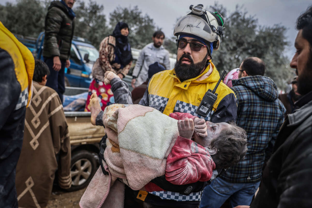 Ανδρας της οργάνωσης Λευκά Κράνη μεταφέρει ένα κορίτσι που διασώθηκε από τον σεισμό στο Χαρίμ της Συρίας