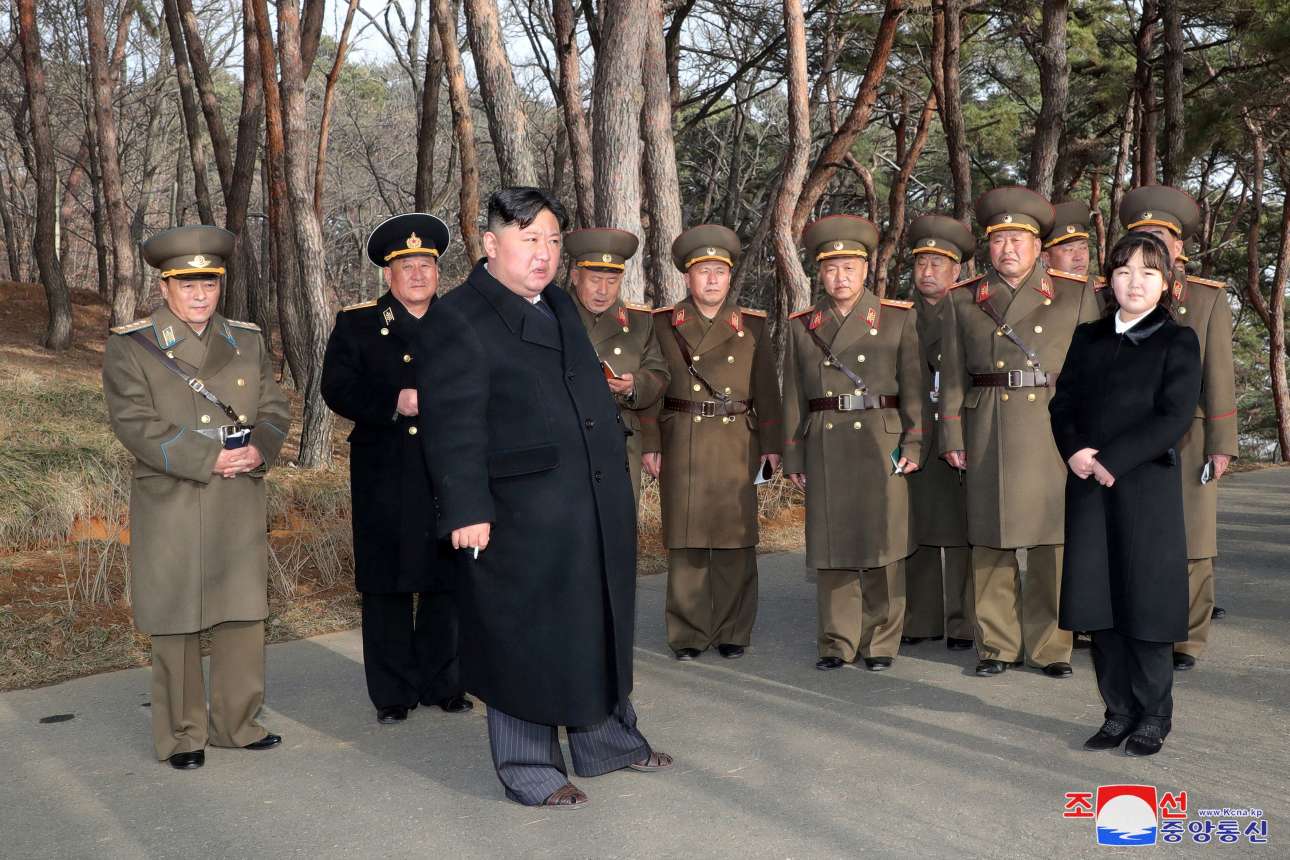 Η εικόνα αυτή δεν δημοσιεύεται επειδή ο άρχων της Βόρειας Κορέας επανεμφάνισε την κόρη του στον στρατό της με αφορμή ασκήσεις Πυροβολικού – πρόκειται για καρέ μόδας: ιδεωδώς ανέκφραστα τα μανεκέν, λανσάρουν παντελόνια ποδήρη σε βαθμό πεδικλώματος, μάλιστα ο Κιμ συνδυάζει τη δική του ριγωτή περισκελίδα με πέδιλα και με βαρύ παλτό