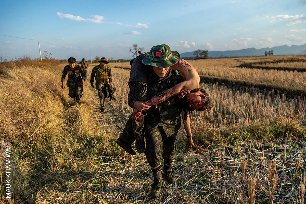 Νοτιοανατολική Ασία και Ωκεανία, Singles, Ενιαία ανάκτηση των νεκρών. Αντιστασιακοί μαχητές των Δυνάμεων της Λαϊκής Αμυνας (PDF) υποχωρούν με τη σορό ενός συντρόφου τους μετά από σύγκρουση με τον στρατό στο Μόε Μπάι, στην πολιτεία Καγιά της Μιανμάρ, 21 Φεβρουαρίου 2022. Το PDF είναι η ένοπλη πτέρυγα μιας παράλληλης κυβέρνησης, που σχηματίστηκε κυρίως από εκδιωχθέντες δημοκρατικούς νομοθέτες, στον απόηχο ενός στρατιωτικού πραξικοπήματος στη Μιανμάρ το 2021. Παράλληλα, μάχεται με περιφερειακές και εθνοτικές ένοπλες ομάδες που επίσης αντιτίθενται στη στρατιωτική δικτατορία της Μιανμάρ 